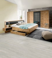 Moderne Schlafzimmermöbel mit einem dreitürigen Schwebetürenschrank, einem Bett mit integrierten Schubkästen und Nachttischen in Holzoptik. Perspektive: seitliche Ansicht des Schlafzimmers.