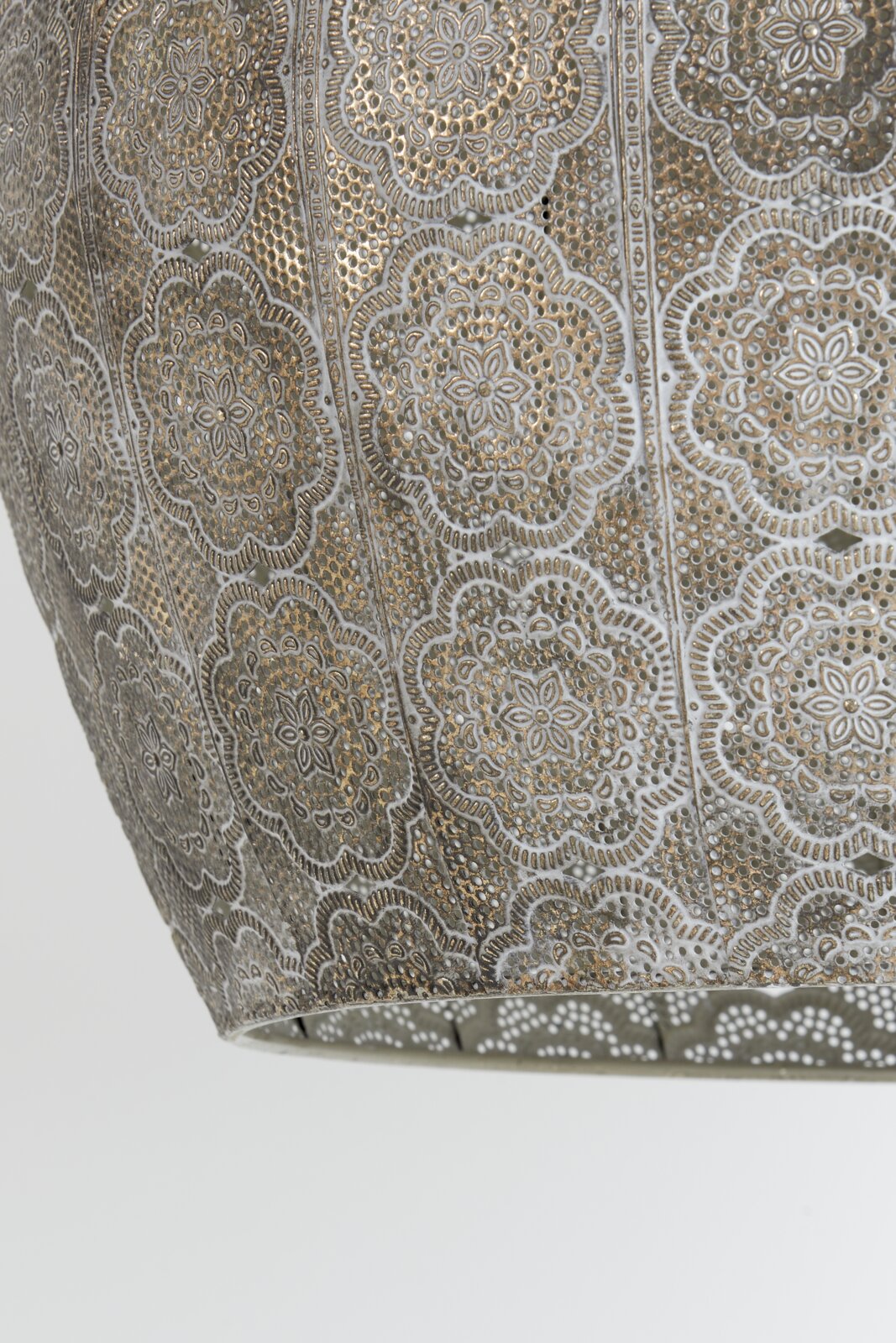Detailfoto van een decoratieve hanglamp met een filigraanpatroon in goud- en zilverkleur.