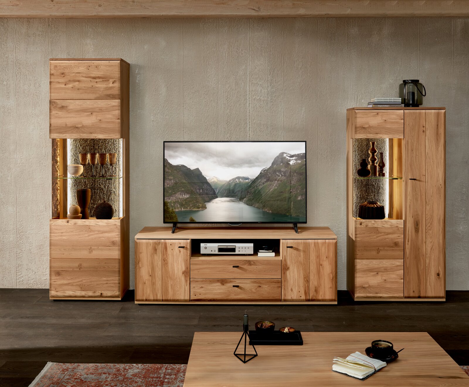 Frontaal aanzicht van een moderne houten woonkamerwand met tv-meubel en twee vitrinekasten met glazen planken en sfeerverlichting, met televisie in het midden