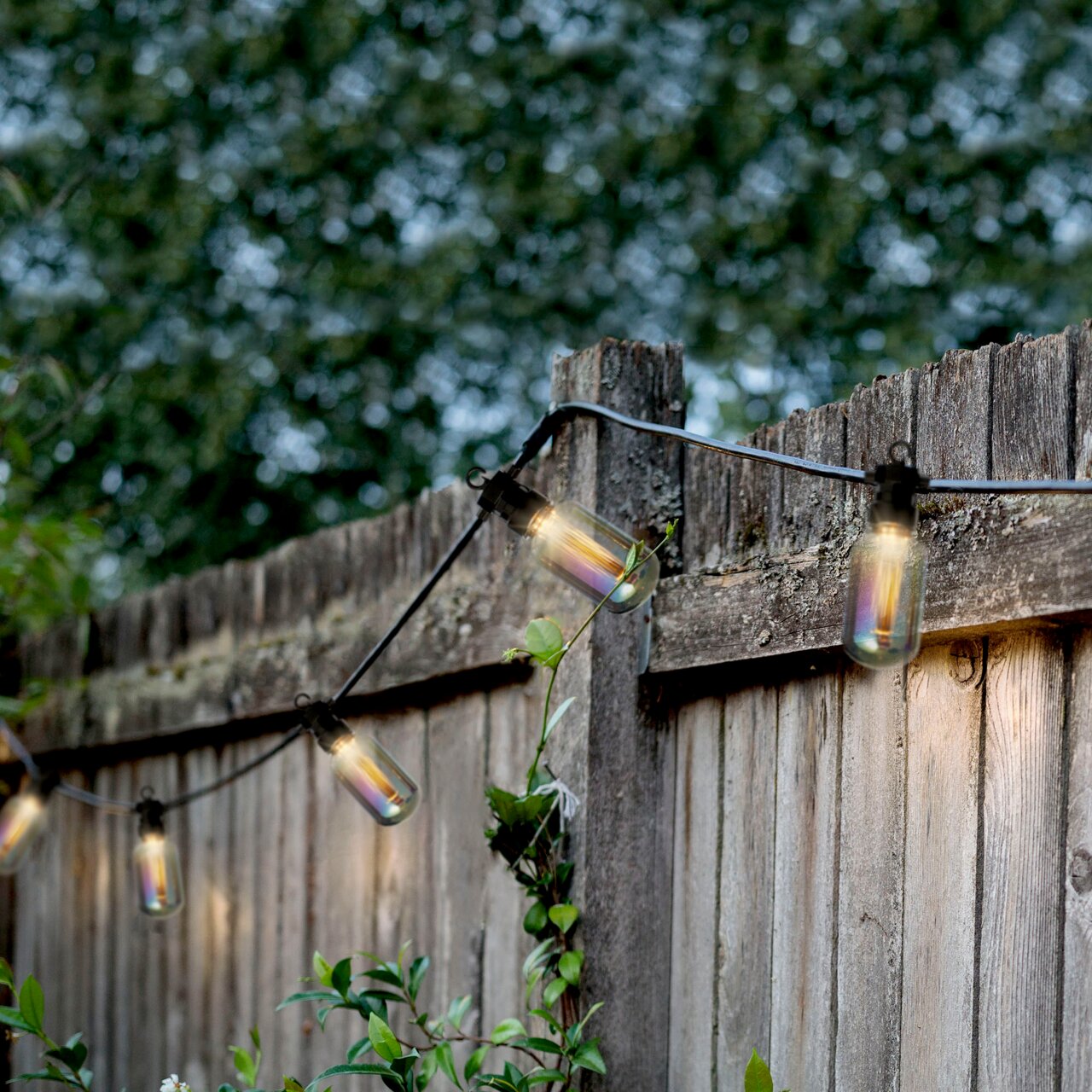 LED-Lichterkette im Freien an einem Holzzaun, seitliche Perspektive