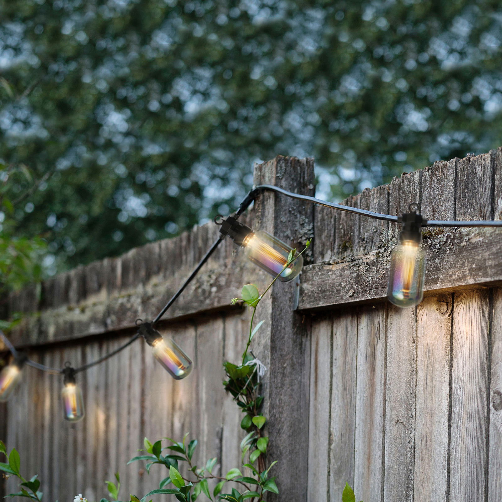 LED-Lichterkette im Freien an einem Holzzaun, seitliche Perspektive