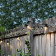 LED-Lichterkette im Freien an einem Holzzaun, seitliche Perspektive