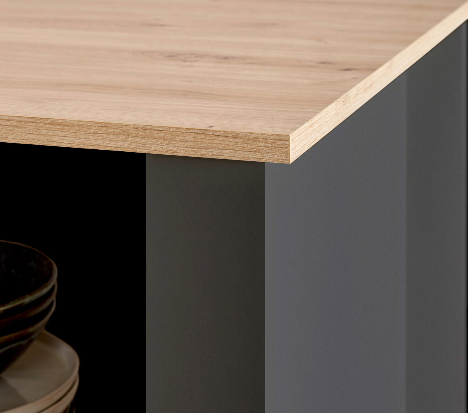 Detailansicht einer Kücheninsel mit Holzarbeitsplatte und grauer Seitenverkleidung, Perspektive von der Ecke.