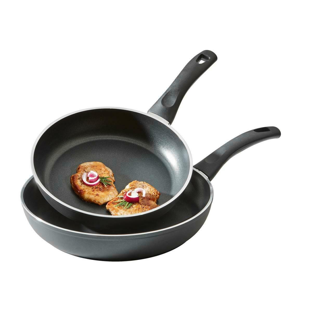 Zwei schwarze Pfannen aus einem Pfannenset, eine mit gebratenem Fleisch und Zwiebeln, aus der Vogelperspektive.