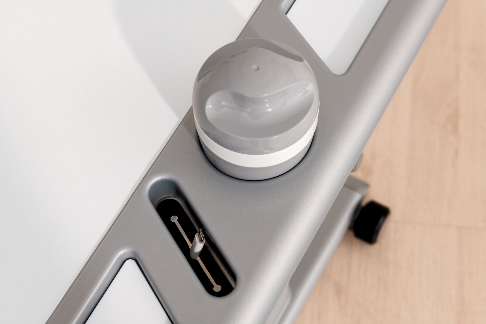 Close-up van een bureau met een grijze draaiknop en een USB-aansluiting, gefotografeerd van bovenaf.