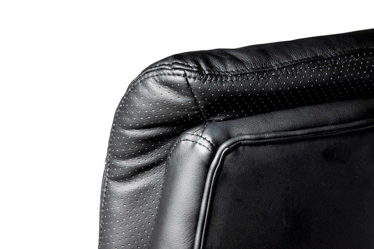 Nahaufnahme der Rückseite eines schwarzen Chefsessels aus Leder mit gepunktetem Muster, seitliche Perspektive