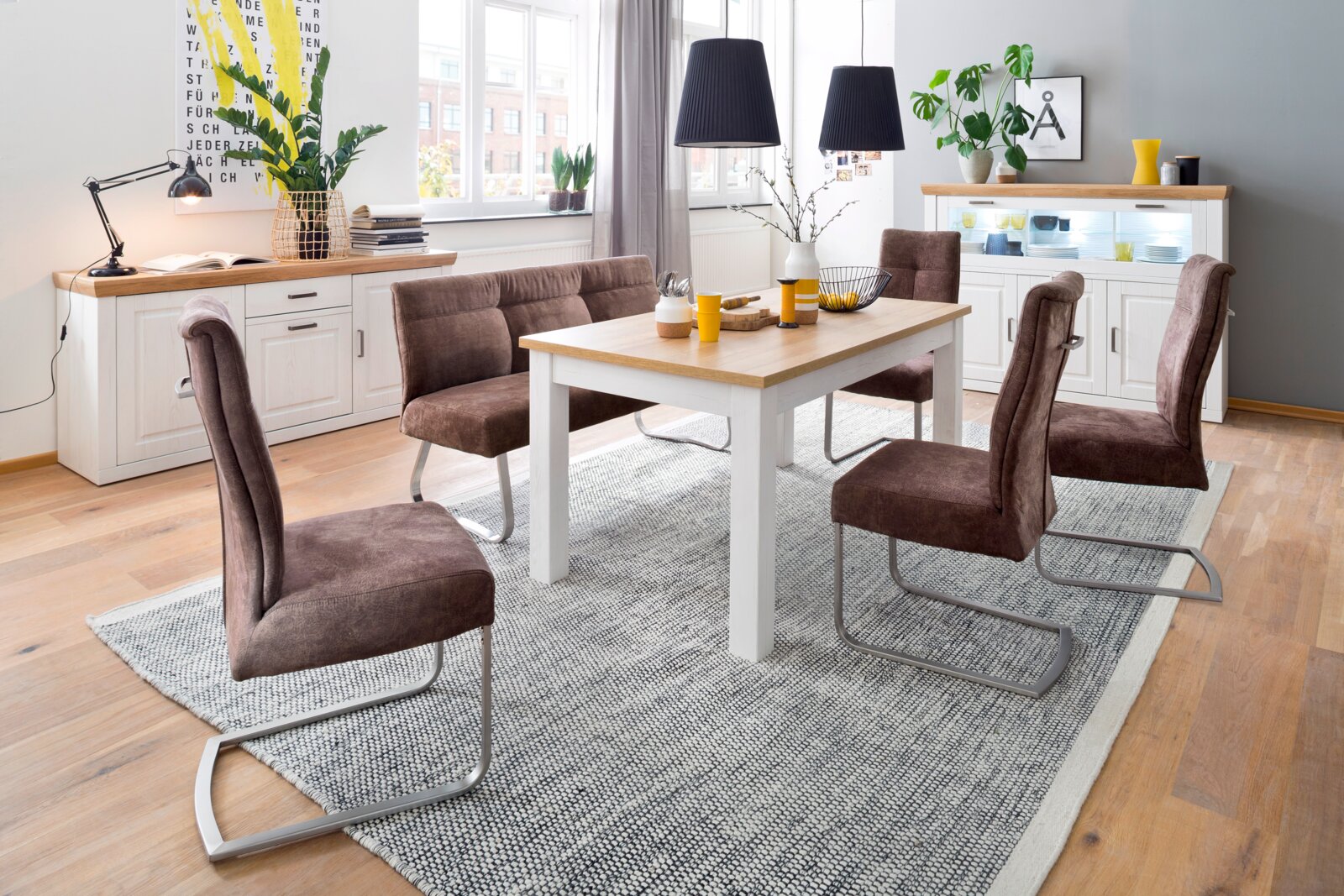 Modernes Esszimmer-Set mit weißem Esstisch mit Holzplatte, brauner gepolsterter Sitzbank und vier Freischwinger-Stühlen auf grauem Teppich, fotografiert in leicht schräger Frontansicht aus Augenhöhe.