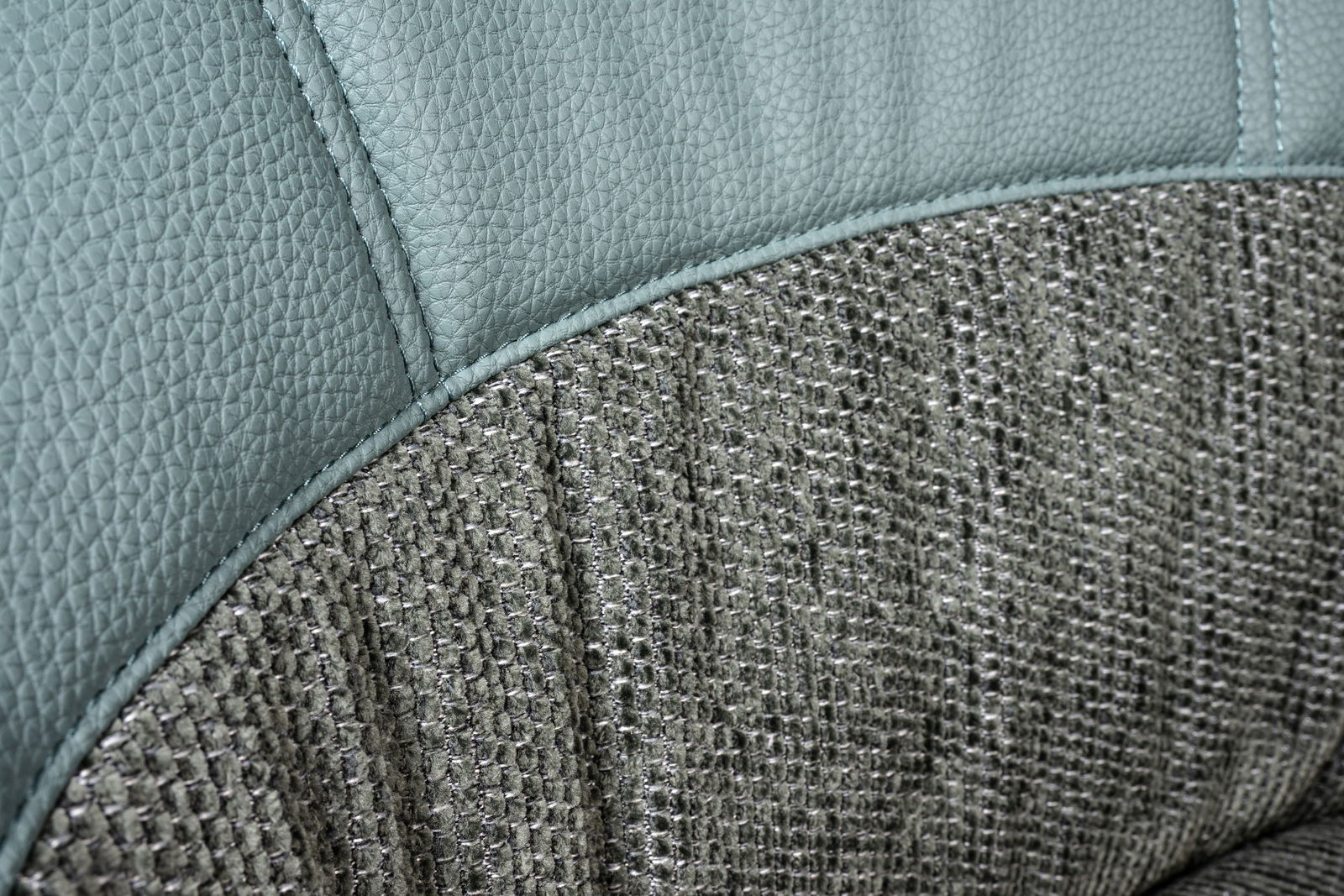 Nahaufnahme eines Drehstuhls mit einer Kombination aus grauem Leder und strukturiertem Stoffbezug.