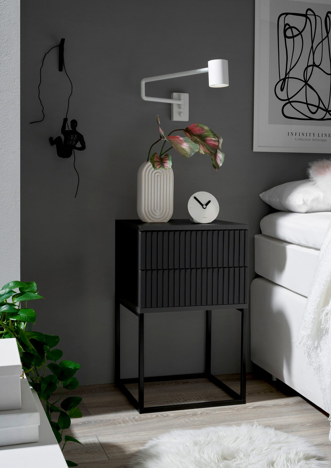 Moderne Nachtkommode in dunklem Design mit zwei Schubladen, dekoriert mit einer Vase und einer Uhr, seitliche Perspektive.