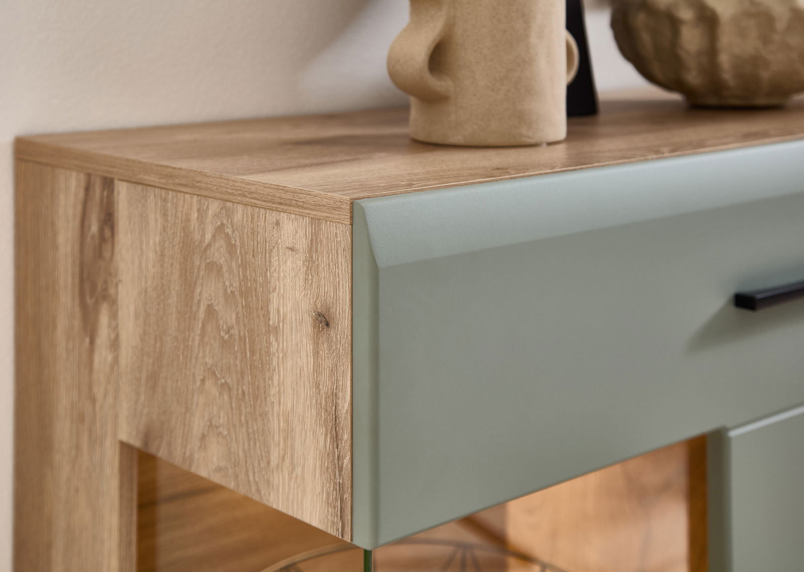 Nahaufnahme einer Wohnwand mit Holzstruktur und grünlicher Front, seitliche Perspektive