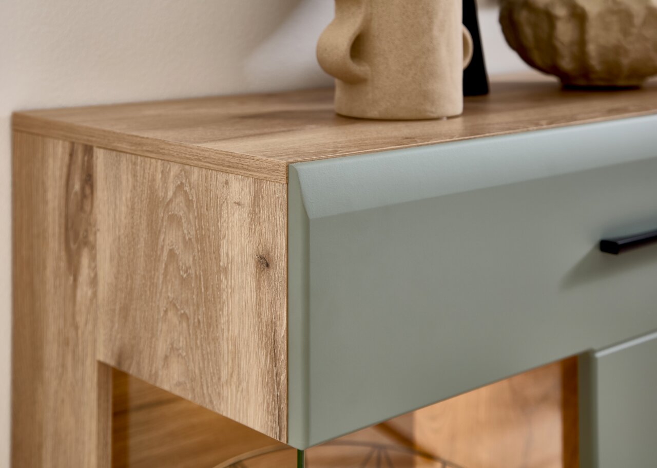 Nahaufnahme einer Wohnwand mit Holzstruktur und grünlicher Front, seitliche Perspektive