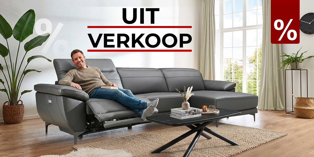 Man ontspant op grijze leren bank in woonkamer, uitverkoop met tot 77% korting.