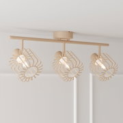 Beigefarbene Deckenleuchte mit drei schwenkbaren Spotköpfen und geometrischen Drahtschirm-Käfigen, eingeschaltet, aus leicht seitlicher Untersicht an der weißen Decke