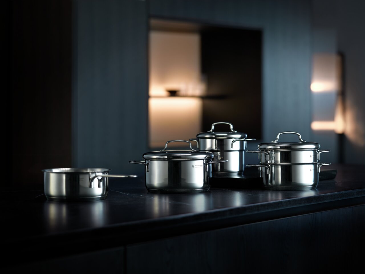 Elegantes 5-teiliges Topfset MINI aus Edelstahl, präsentiert auf einer dunklen Küchenarbeitsplatte in einem modernen, stilvollen Ambiente. Perspektive von vorne links.