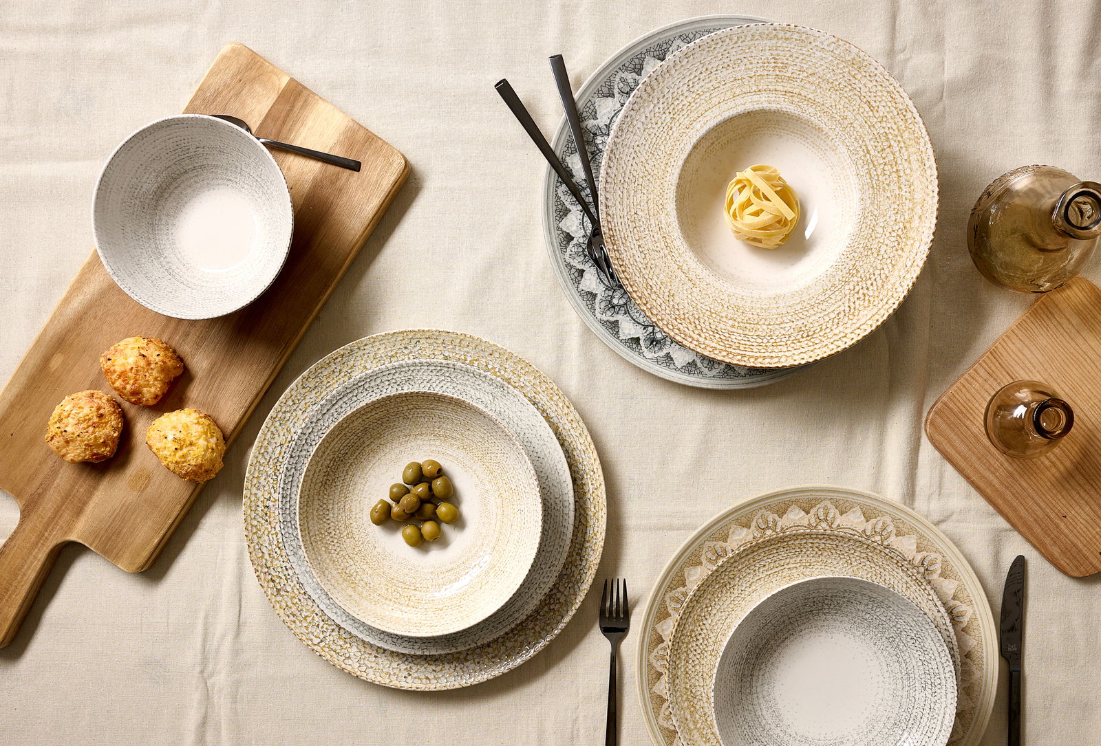 Ritzenhoff & Breker Dessertteller RIMINI Vogelperspektive auf einen gedeckten Tisch mit verschiedenen Tellern und Schalen, darunter ein Dessertteller mit Oliven, auf einem hellen Tischtuch.