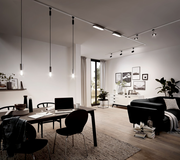 Moderne Wohnzimmerszene mit Schienensystem an der Decke, das mehrere Hängeleuchten und Strahler trägt. Perspektive von der Seite des Esstisches aus.