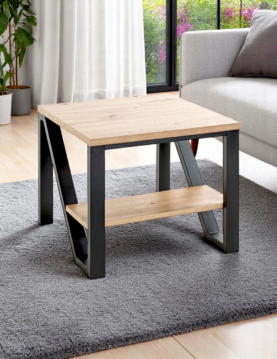 Moderner Couchtisch mit heller Holzplatte und schwarzem Metallgestell mit Ablage, im Wohnzimmer neben grauem Sofa auf Teppich, Perspektive: leicht seitliche Frontansicht