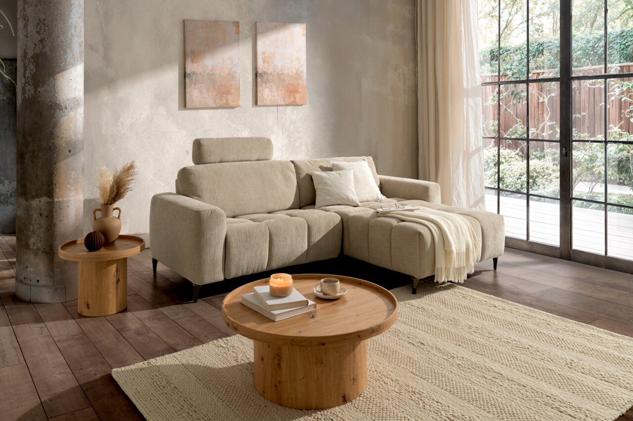 Z2 Ecksofa ROSALY Beige Ecksofa mit verstellbarer Kopfstütze und Ottomane, in einem modernen Wohnzimmer mit großen Fenstern und Holztischen, aus der Perspektive von vorne rechts.