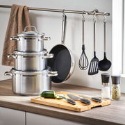 Elegantes 13-teiliges Gourmet-Set mit Töpfen, Pfanne, Küchenutensilien und Schneidebrett in moderner Küchenumgebung, seitliche Perspektive.