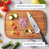 Vogelperspektive auf ein Schneidebrett mit einem Messer aus Edelstahl, umgeben von geschnittenem Gemüse und Zwiebeln.