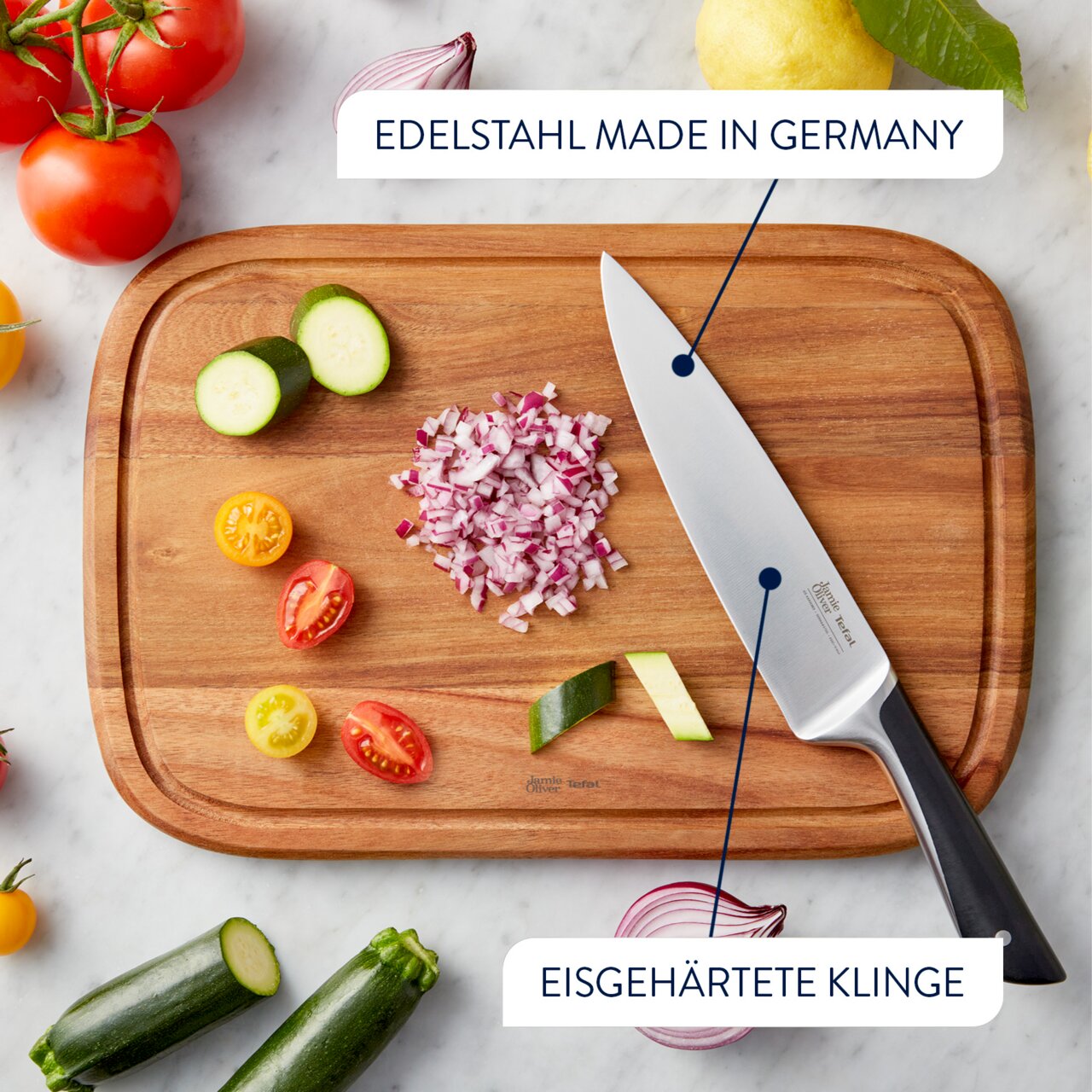 Vogelperspektive auf ein Schneidebrett mit einem Messer aus Edelstahl, umgeben von geschnittenem Gemüse und Zwiebeln.