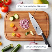Vogelperspektive auf ein Schneidebrett mit einem Messer aus Edelstahl, umgeben von geschnittenem Gemüse und Zwiebeln.