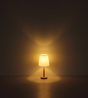 Tischleuchte mit warmem Licht, frontal betrachtet, auf einem Tisch stehend