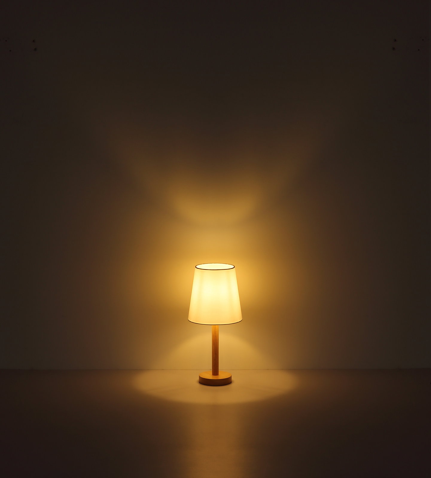 Tischleuchte mit warmem Licht, frontal betrachtet, auf einem Tisch stehend