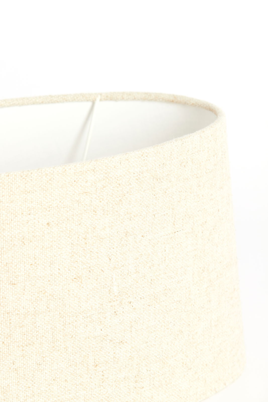Nahaufnahme eines cremefarbenen, ovalen Lampenschirms aus Stoff, seitliche Perspektive.