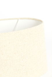 Nahaufnahme eines cremefarbenen, ovalen Lampenschirms aus Stoff, seitliche Perspektive.