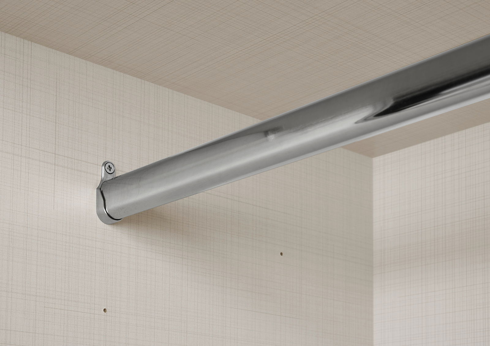 Nahaufnahme einer stabilen, silbernen Kleiderstange in einem Schwebetürenschrank, montiert an einer hellen, strukturierten Innenwand.