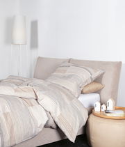 Bettwäsche-Set in Beige- und Brauntönen mit Streifenmuster auf einem Bett, seitliche Perspektive