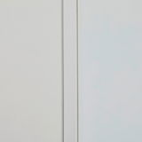 Nahaufnahme eines schmalen Mehrzweckschranks mit weißer Tür und glatter Oberfläche, seitliche Perspektive.