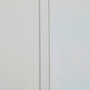 Nahaufnahme eines schmalen Mehrzweckschranks mit weißer Tür und glatter Oberfläche, seitliche Perspektive.