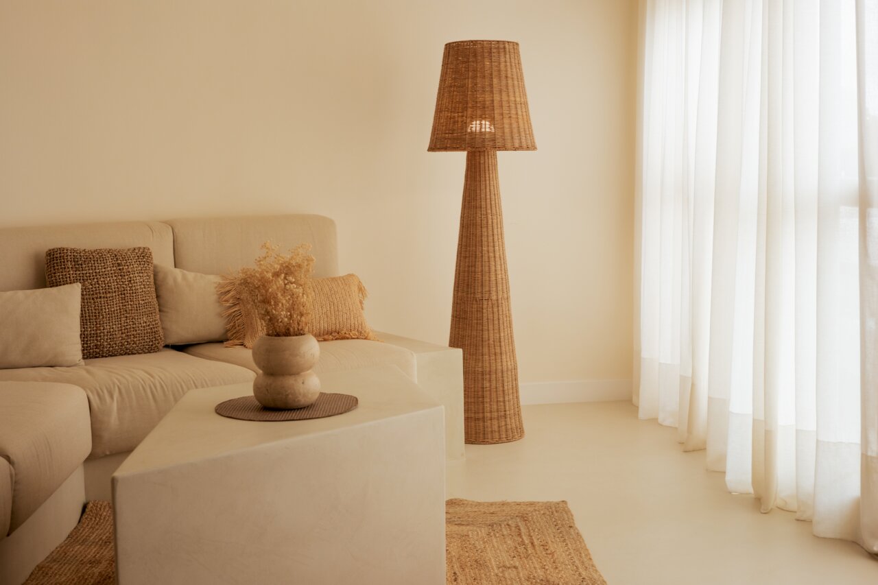 Natürliche Rattan-Stehleuchte in einem gemütlichen Wohnzimmer, seitliche Perspektive