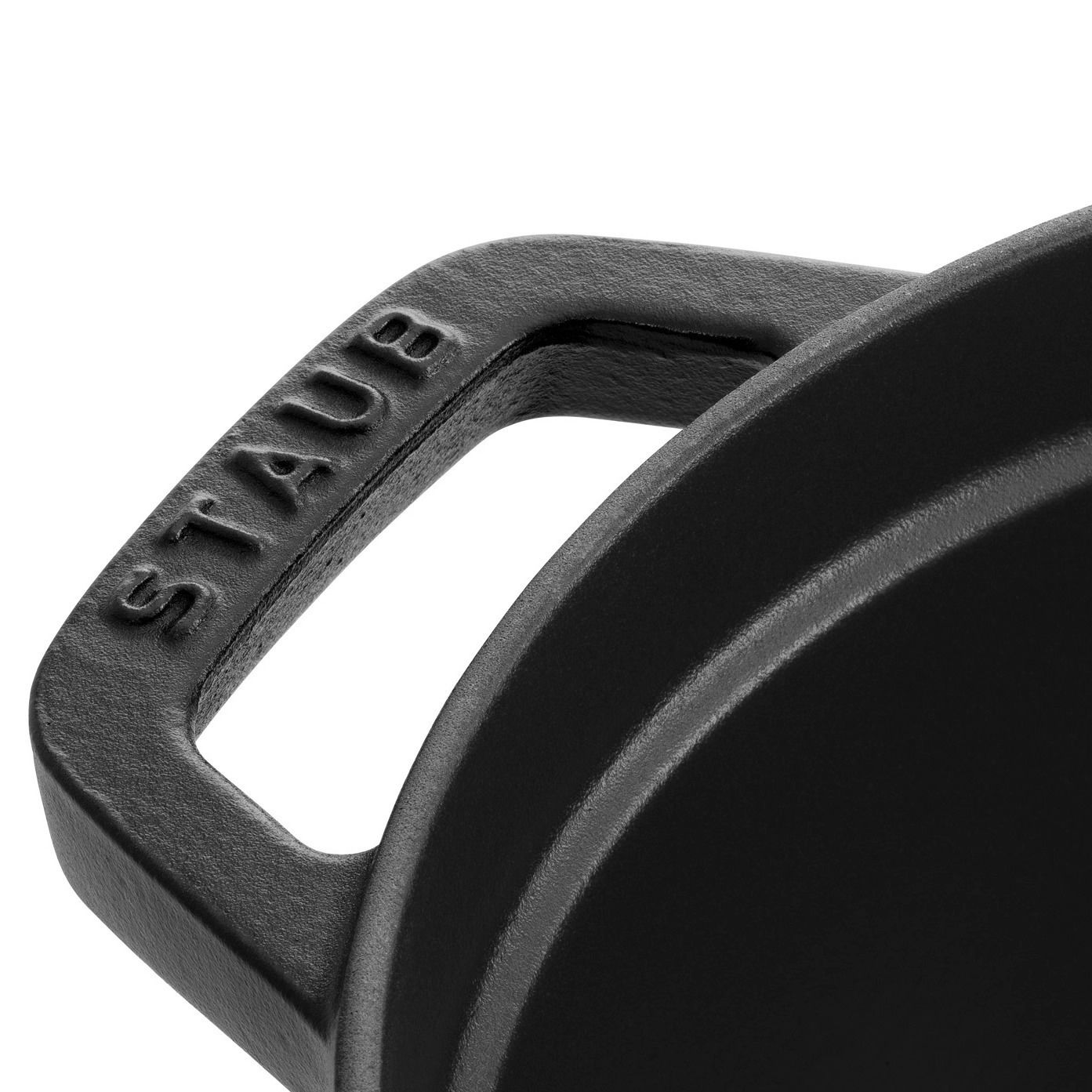 Nahaufnahme eines schwarzen ovalen Bräters mit Griff, Marke STAUB, von oben betrachtet.