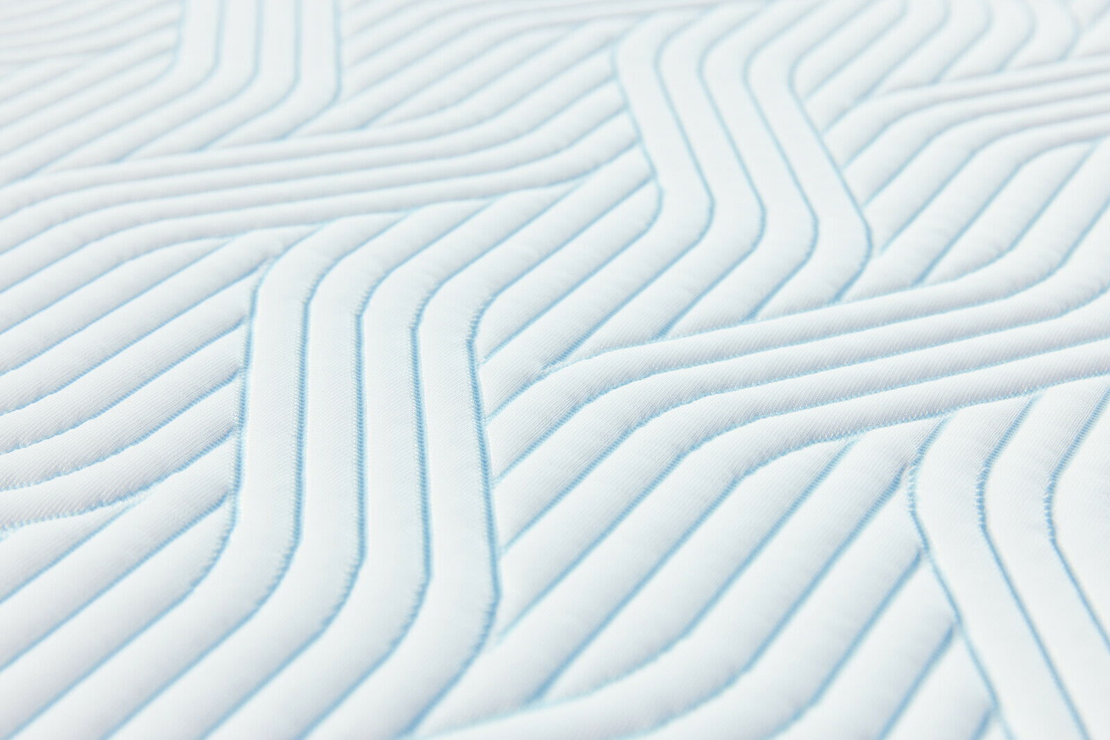 Tempur Topper Firm PRO PLUS SMARTCOOL Nahaufnahme eines gesteppten Matratzen-Toppers mit geometrischem Muster in diagonaler Perspektive