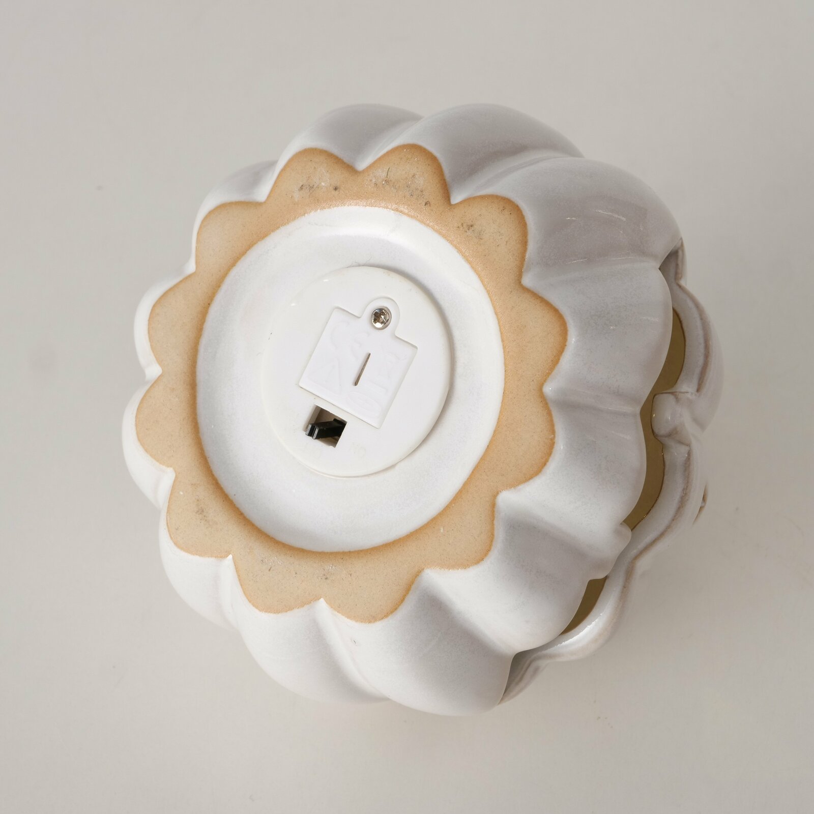 Unteransicht eines weißen, dekorativen Kürbisses mit Batteriefach.