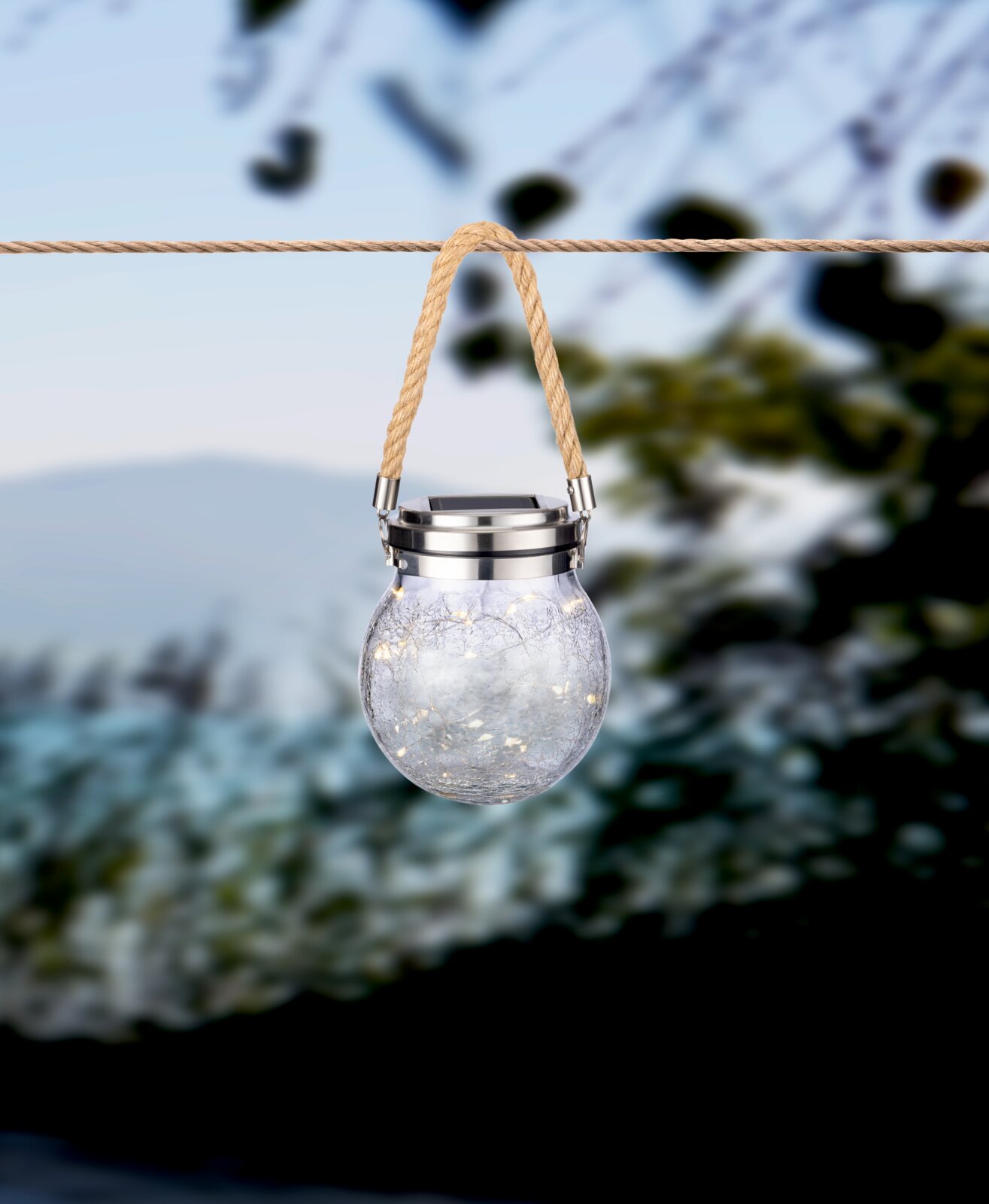Ambia Garden Solarleuchte SOLARLEUCHTE Solarleuchte in Form eines Glases mit Seilaufhängung, von vorne fotografiert, im Freien aufgehängt.