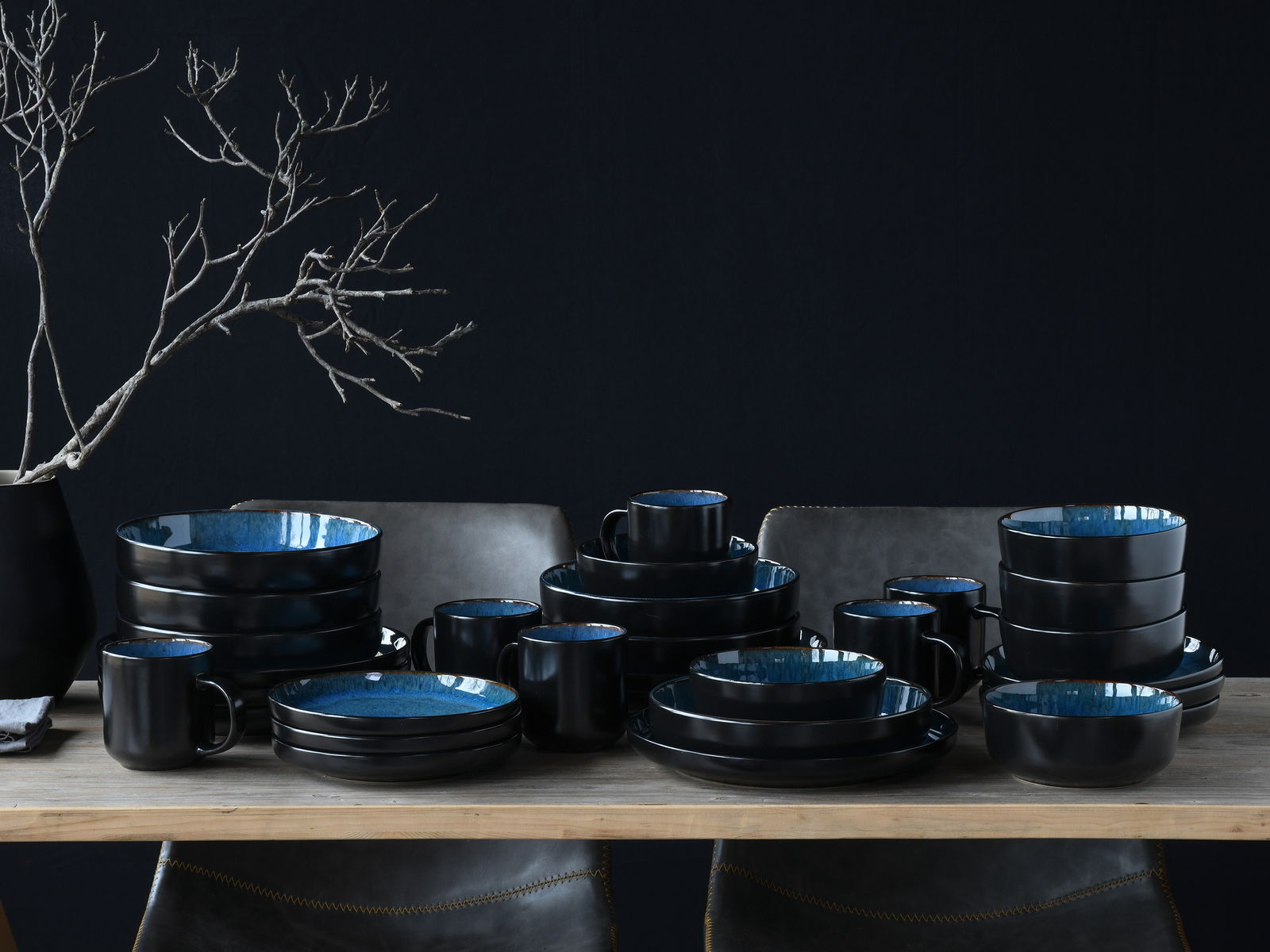 Kombiservice 30-tlg. Blue in eleganter schwarzer und blauer Keramik, auf einem Tisch arrangiert, seitliche Perspektive.