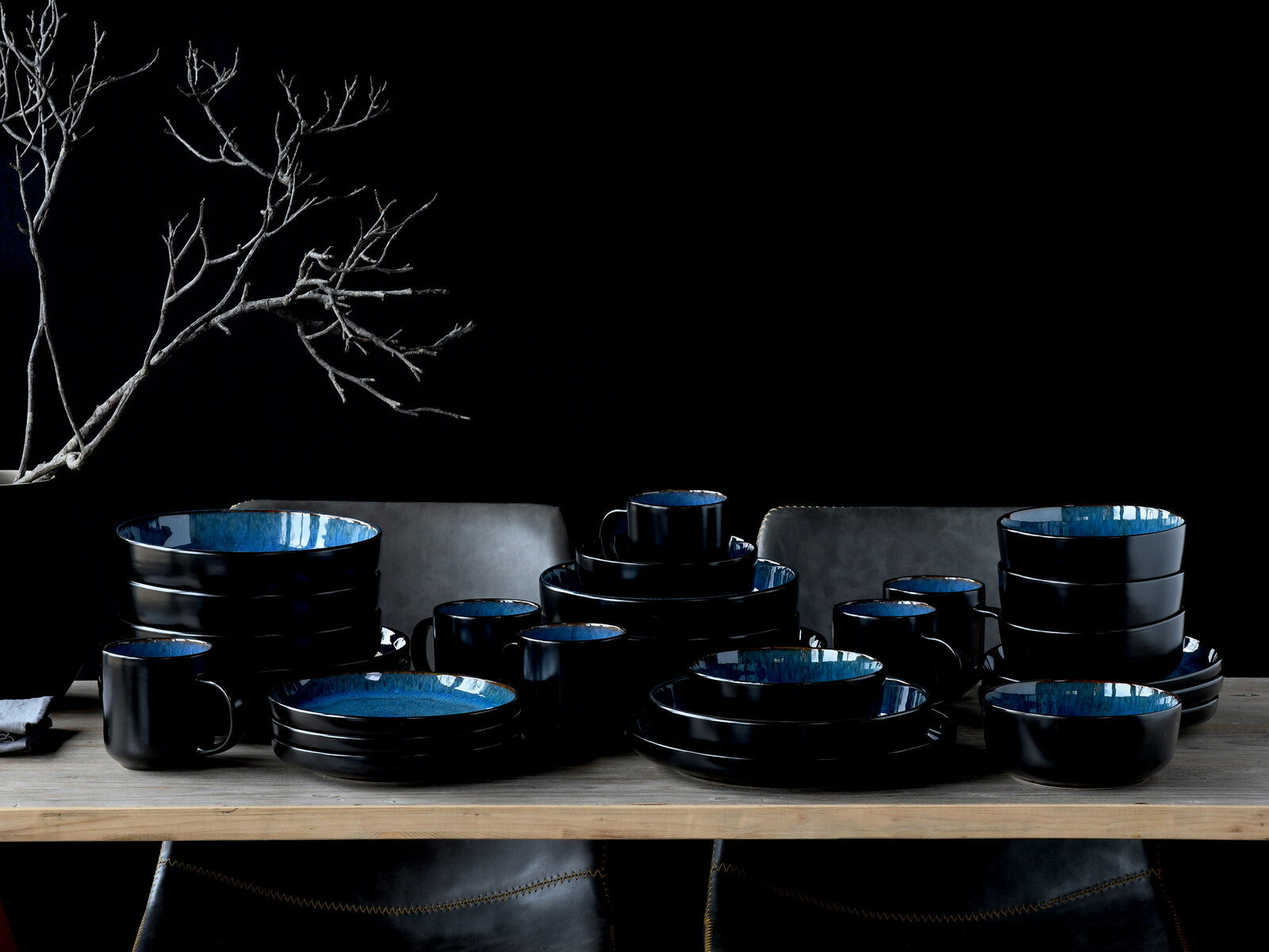 Kombiservice 30-tlg. Blue in eleganter schwarzer und blauer Keramik, auf einem Tisch arrangiert, seitliche Perspektive.