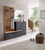 Moderne Kompaktgarderobe in einem hellen Raum, bestehend aus einer Holzpaneelwand mit Haken, einem Spiegel und grauen Schränken. Perspektive von vorne.