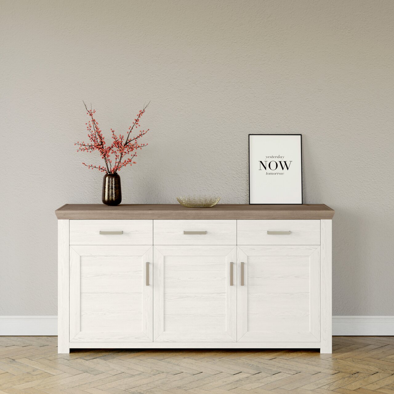 Weißes Sideboard mit drei Schubladen und drei Türen, dekoriert mit einer Vase mit roten Zweigen und einem gerahmten Zitat, aus frontaler Perspektive.