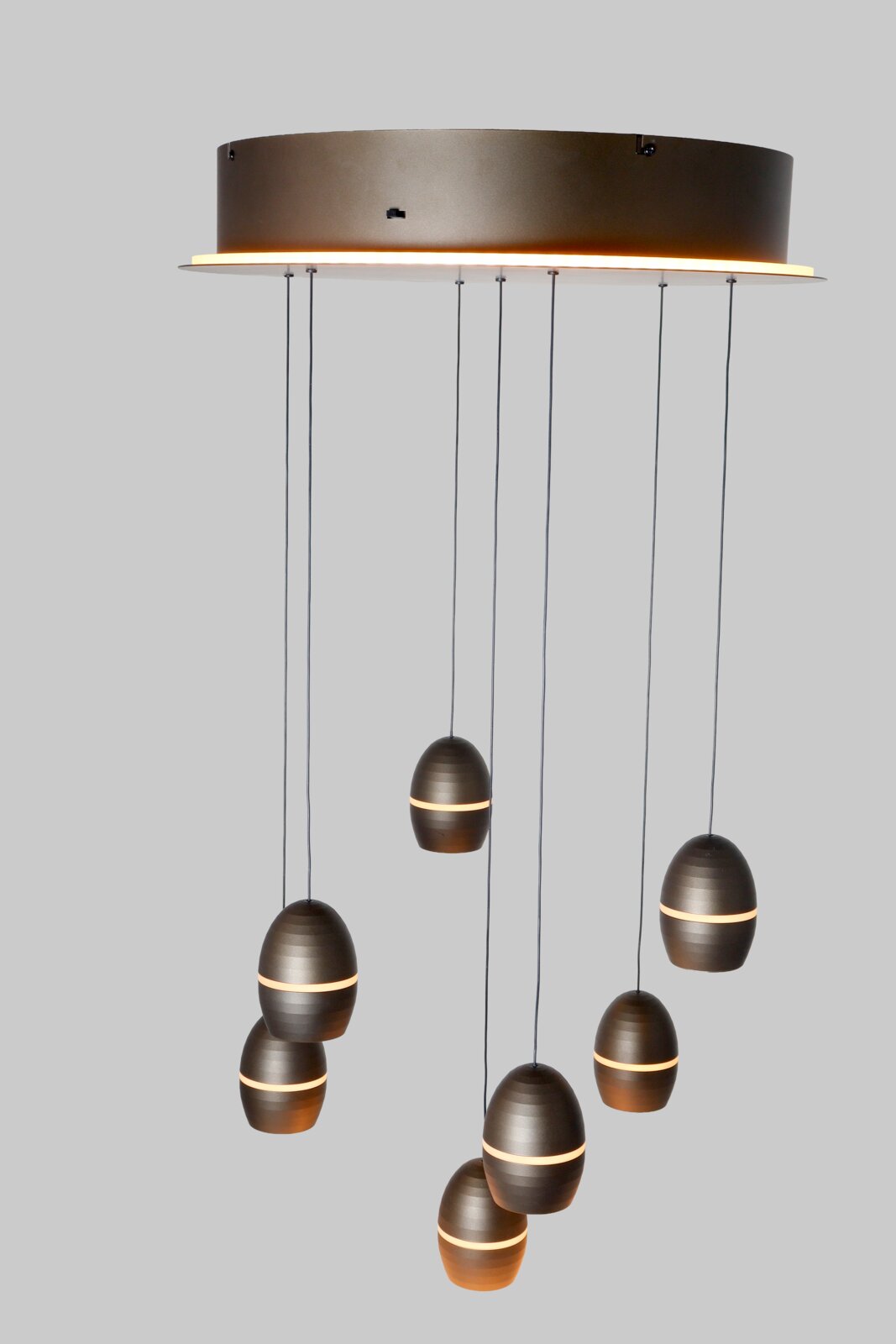 Moderne mehrflammige Pendelleuchte mit runder Deckenplatte und mehreren eiförmigen Metall-Schirmen in dunklem Bronze/Anthrazit mit warmem Lichtband, Frontansicht leicht von unten