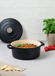 Schwarzer Kochtopf 24cm mit Deckel, gefüllt mit einem Gericht, auf einer Küchenarbeitsplatte, seitliche Perspektive.