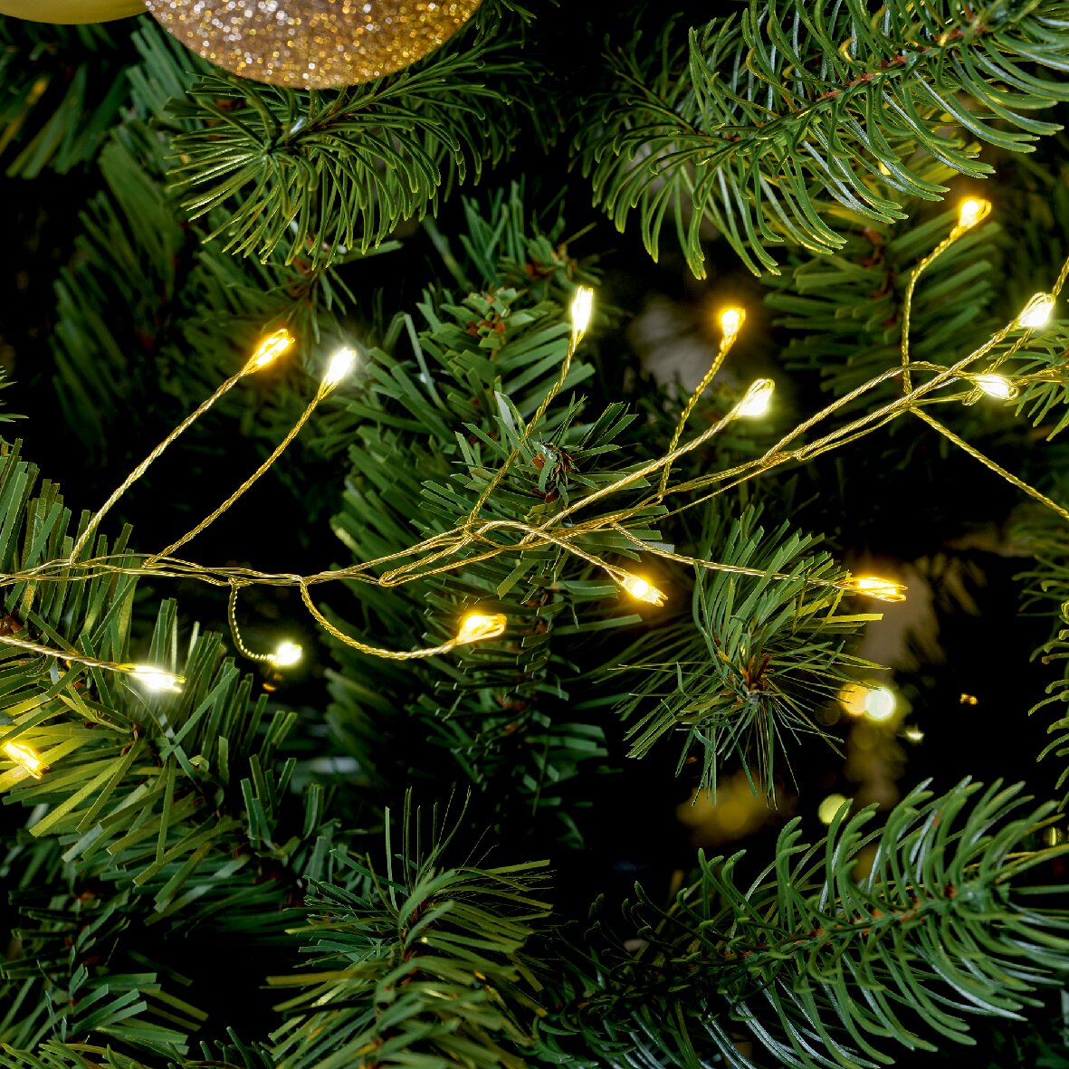 Nahaufnahme von Micro LED Lichterkette in einem Weihnachtsbaum, warmweiß leuchtend.