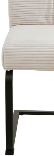 Nahaufnahme eines modernen Schwingstuhls mit cremefarbenem, geripptem Stoffbezug und schwarzem Metallgestell, seitliche Perspektive.