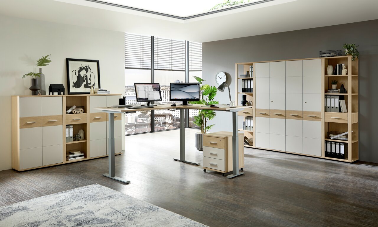 Een moderne kantooromgeving met een in hoogte verstelbaar hoekbureau, omringd door archiefkasten en boekenkasten, gezien vanuit een lichte, ruime kamer met grote ramen.