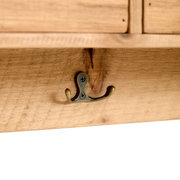 Close-up van een houten plank met een antieke dubbele metalen haak, gezien van onderaf.