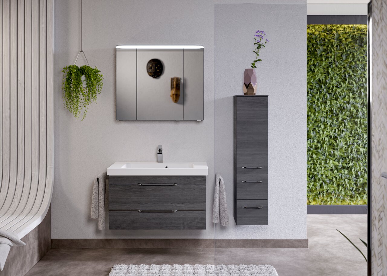 Moderne Badezimmermöbel in dunklem Holzton, bestehend aus einem Waschtisch mit zwei Schubladen und einem hohen Schrank, mit Spiegel und Pflanzen, aus frontaler Perspektive.